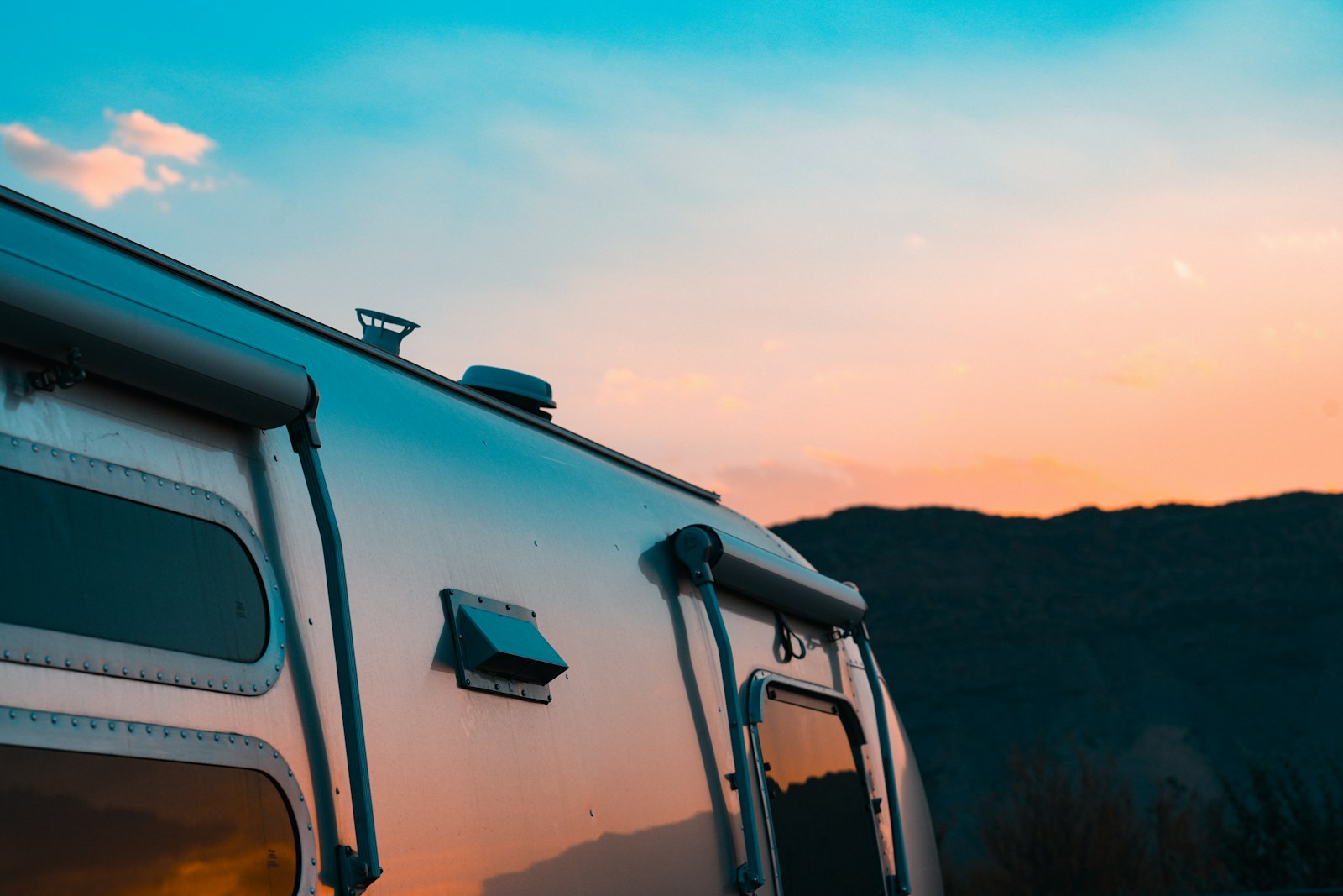 Silver travel trailer against a sunset sky.